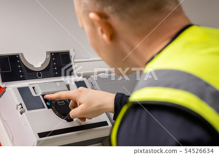 Electrician Checking Smoke Detector In Server Room Electrician Checking Smoke Detector In Server Room 54526634
