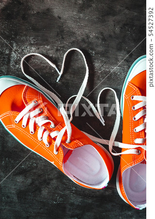 Yellow-orange sneakers on a grunge concrete dark Yellow-orange sneakers on a grunge concrete dark 54527392