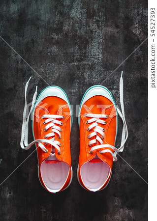 red sneakers with untied laces on a dark concrete red sneakers with untied laces on a dark concrete 54527393