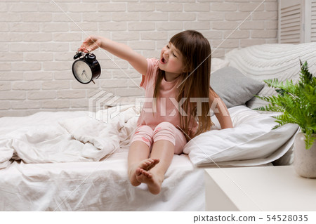 little child girl in pyjamas with clock little child girl in pyjamas with clock 54528035
