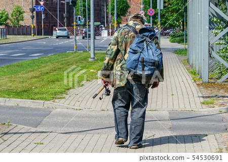 a drunk fisherman with a backpack and a fishing 54530691