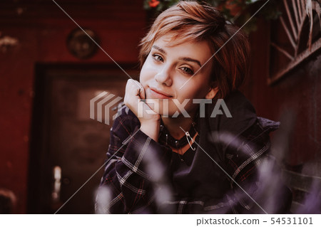 Outdoor portrait of young woman with short red hair posing with lavender flower 54531101