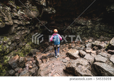 Woman traveler explore lava tunnel in Iceland. Woman traveler explore lava tunnel in Iceland. 54535059