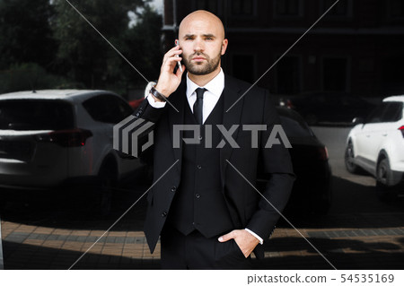 businessman with a bag near the office talking on the phone 54535169