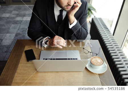 Close up of handsome businessman, working on laptop in restaurant Close up of handsome businessman, working on laptop in restaurant 54535186