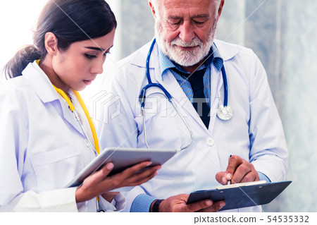 Doctors working with tablet computer at hospital. Doctors working with tablet computer at hospital. 54535332
