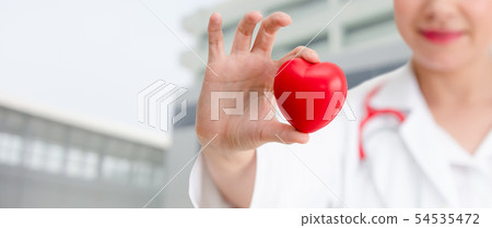 Doctor holding a red heart at hospital office. 54535472