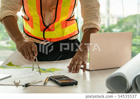 Young man architect or engineer working at desk. 54535537