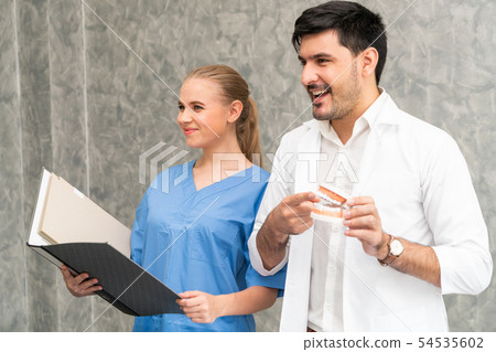 Dentist and nurse working in dental office. 54535602