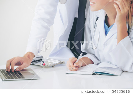 Doctor at hospital works on computer with partner. Doctor at hospital works on computer with partner. 54535616