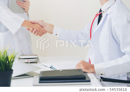 Doctor at hospital shakes hand with another doctor Doctor at hospital shakes hand with another doctor 54535618