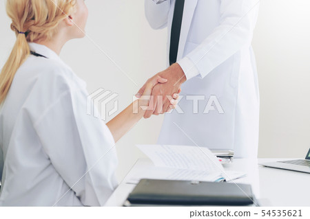 Doctor at hospital shakes hand with another doctor Doctor at hospital shakes hand with another doctor 54535621