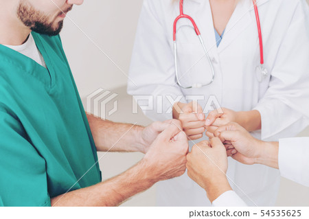 Doctor, surgeon and nurse join hands together. 54535625