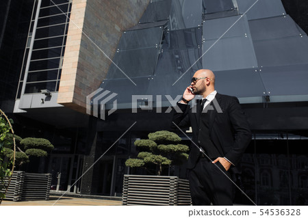 businessman with a bag near the office talking on the phone businessman with a bag near the office talking on the phone 54536328