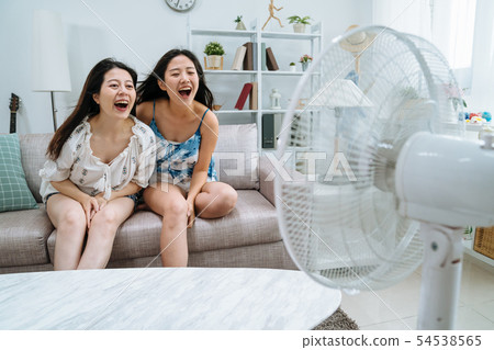 friend sitting on couch playing with electric fan 54538565
