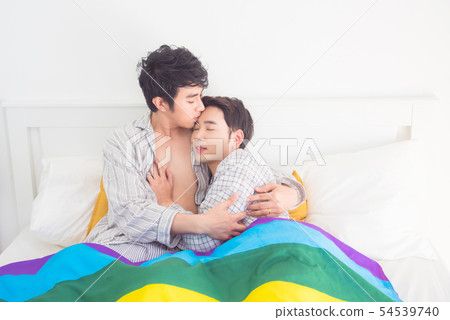 Young Gay couple wearing pajamas lying on bed 54539740