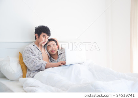 Young Gay couple wearing pajamas lying on bed 54539741