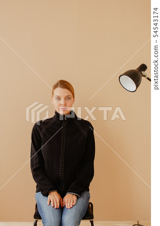 Short-haired woman in chair in front of studio light Short-haired woman in chair in front of studio light 54543174