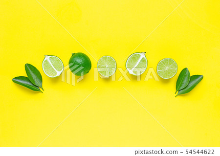 Limes with leaves  on yellow background. 54544622