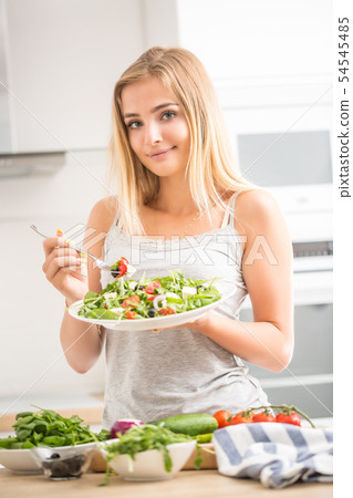 Young happy blonde girl eating healthy salad from 54545485