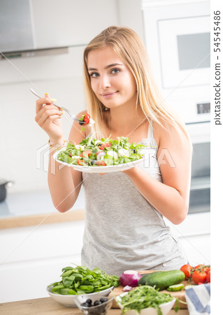 Young happy blonde girl eating healthy salad from Young happy blonde girl eating healthy salad from 54545486