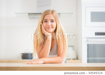 Young cheerful blonde girl in the house kitchen. Young cheerful blonde girl in the house kitchen. 54545514