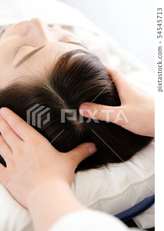 Female and practitioner hands receiving scalp massage 54545713