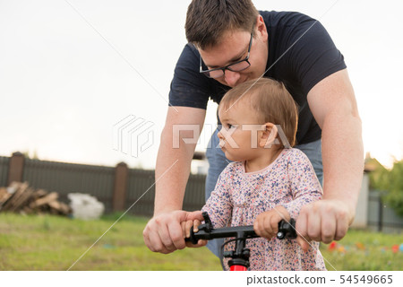 Young father spend time with Cute little one years old toddler girl child and balance bike, father's 54549665