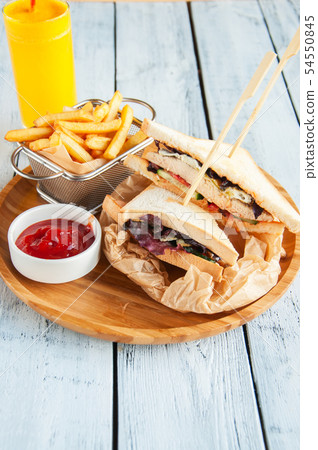 Two club sandwiches and fries on a wooden plate. Two club sandwiches and fries on a wooden plate. 54550845