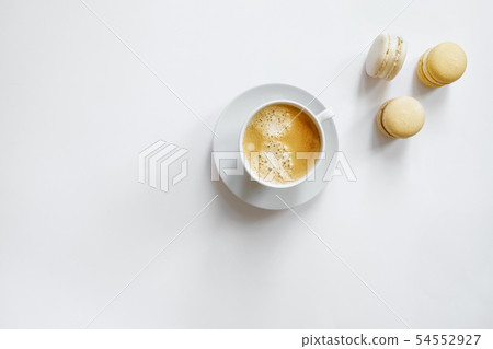 White cup of coffee with yellow macarons. 54552927