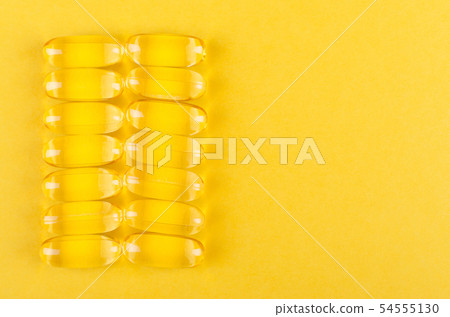 yellow capsules on yellow background with copy spa 54555130