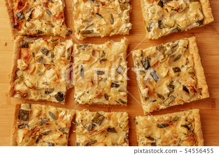 A closeup photo of a homemade zucchini and goat cheese pie with sage, shot from the top on a wooden 54556455