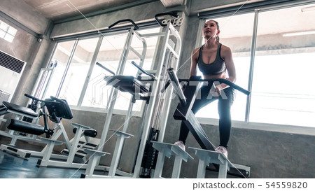 Woman is lifting weight on squat workout machine 54559820