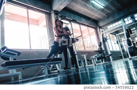 Female is working out on Ab machine with trainer 54559822