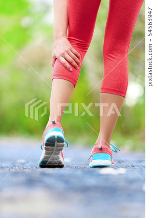 Muscle injury - woman running clutching calf muscle 54563947
