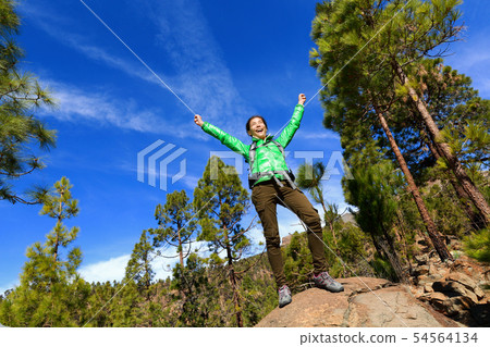 Hiking woman reaching summit cheering in forest Hiking woman reaching summit cheering in forest 54564134