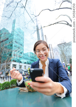 Young business woman on smartphone in lunch break 54564350