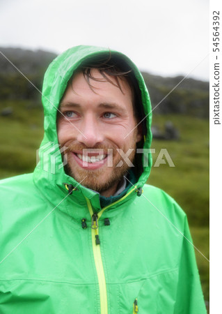 Rain jacket - man smiling outdoors on rainy day Rain jacket - man smiling outdoors on rainy day 54564392