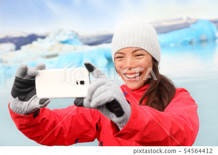 Woman taking selfie photo by Jokulsarlon Iceland Woman taking selfie photo by Jokulsarlon Iceland 54564412