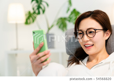看智能手機的婦女在屋子裡 看智能手機的婦女在屋子裡 54568820