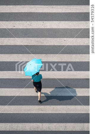 Young chinese woman with an umbrella walking on a zebra crossing 54579316