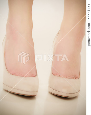 Closeup of female feet in beige high heels. Closeup of female feet in beige high heels. 54581433