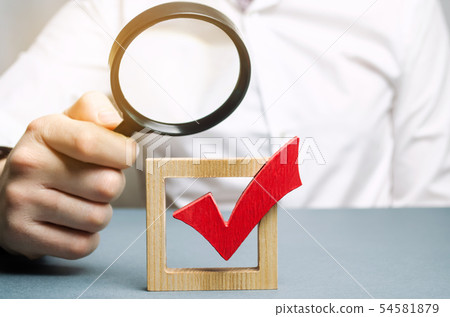 A man examines a red check mark through  54581879