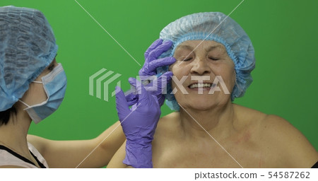 Elderly female in protective hat. Doctor 54587262
