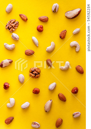 A variety of nuts are scattered on a yellow A variety of nuts are scattered on a yellow 54592284