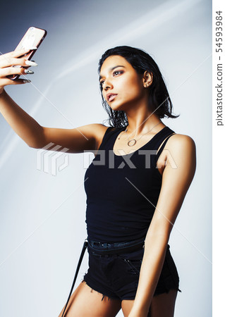 young pretty indian girl posing with phone isolated on white background, lifestyle modern fashion young pretty indian girl posing with phone isolated on white background, lifestyle modern fashion 54593984