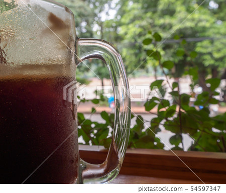 Close up the coffee mug behind the leaves 54597347