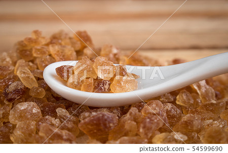 Natural rock sugar in white spoon on rustic table Natural rock sugar in white spoon on rustic table 54599690