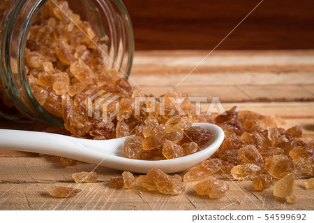 Natural rock sugar in white spoon on rustic table Natural rock sugar in white spoon on rustic table 54599692