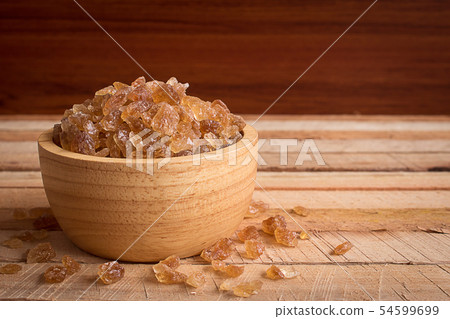 Natural rock sugar in wooden bowl on rustic table Natural rock sugar in wooden bowl on rustic table 54599699